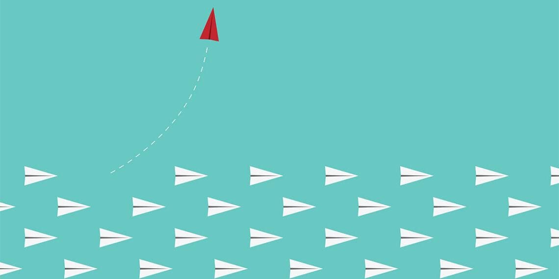 red paper airplane leaves other paper airplanes