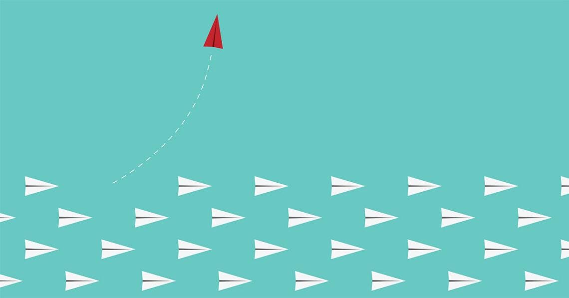 red paper airplane leaves other paper airplanes