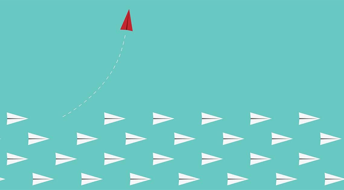 red paper airplane leaves other paper airplanes