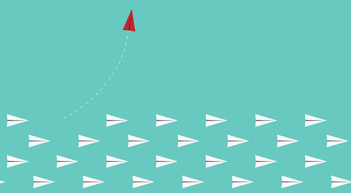 red paper airplane leaves other paper airplanes