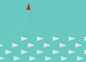 red paper airplane leaves other paper airplanes