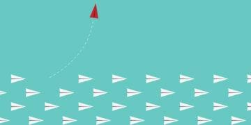 red paper airplane leaves other paper airplanes