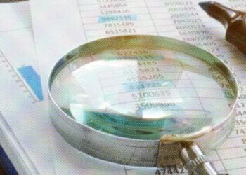 magnifying glass and highlighter on stack of paper