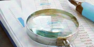 magnifying glass and highlighter on stack of paper
