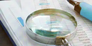 magnifying glass and highlighter on stack of paper