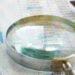magnifying glass and highlighter on stack of paper
