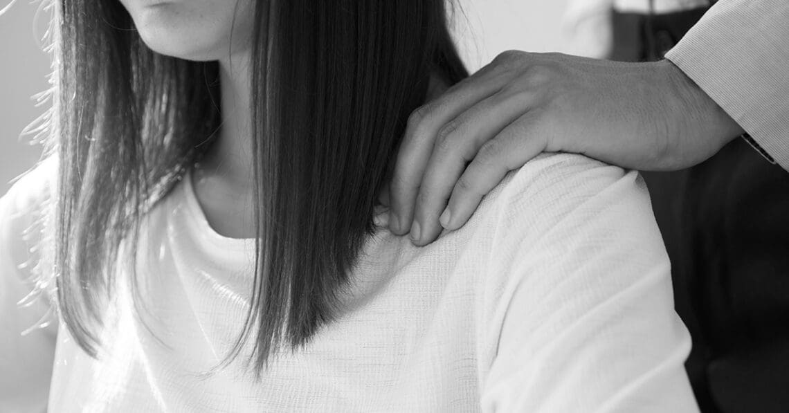 A man puts his hands on a woman's shoulders