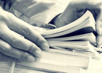 businesswoman looking at stack of documents for audit