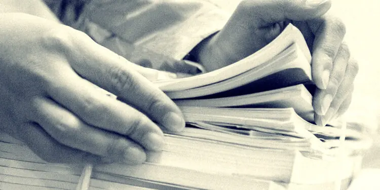 businesswoman looking at stack of documents for audit