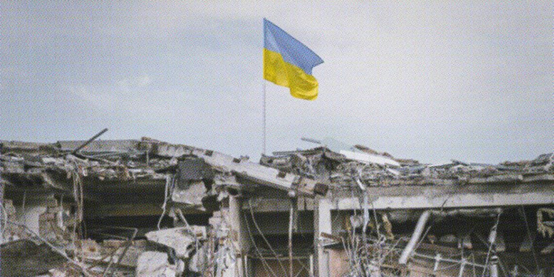 ukraine flag flying above damaged building