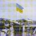 ukraine flag flying above damaged building