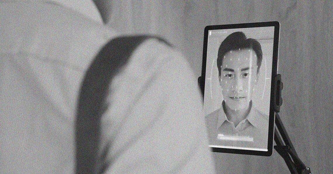 man using facial recognition tablet at work