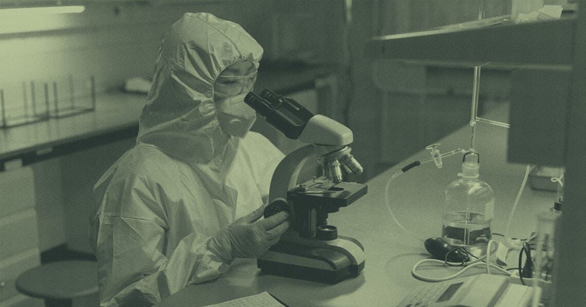 lab technician looking at sample in microscope