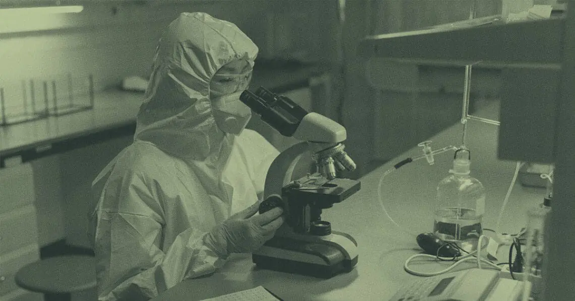 lab technician looking at sample in microscope