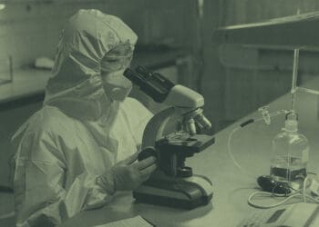 lab technician looking at sample in microscope