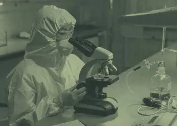 lab technician looking at sample in microscope