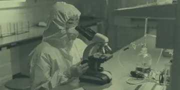 lab technician looking at sample in microscope