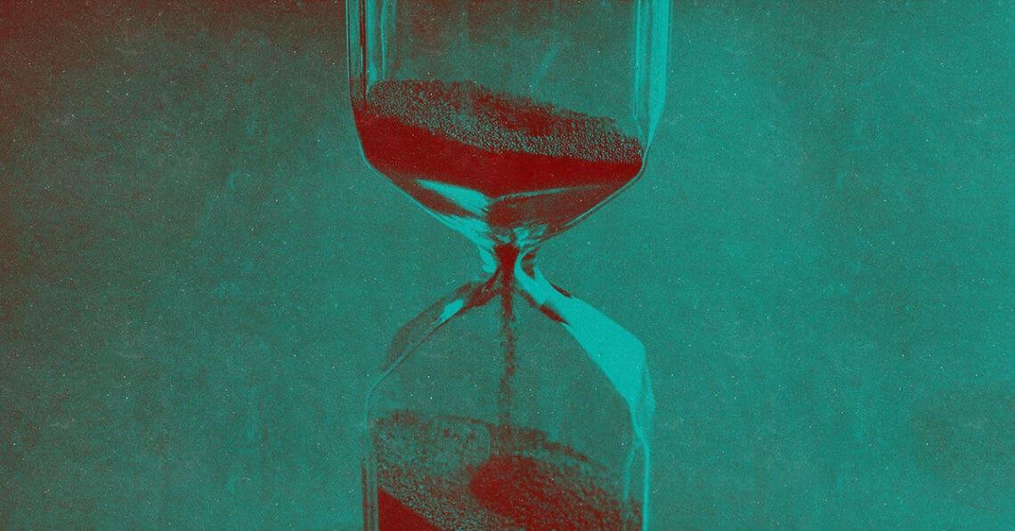 An hourglass with sand flowing into its bottom.