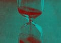 An hourglass with sand flowing into its bottom.