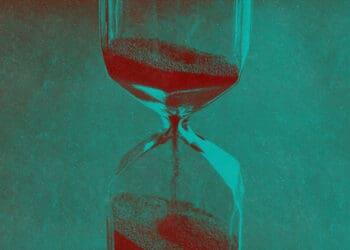 An hourglass with sand flowing into its bottom.