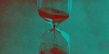 An hourglass with sand flowing into its bottom.